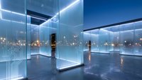 Modern glass office interior with panoramic city views at night featuring LED lighting and reflective surfaces for corporate architecture design.