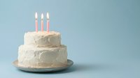 White frosted birthday cake with three pink candles on blue background for celebration party dessert bakery anniversary milestone special occasion.