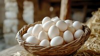 Fresh white chicken eggs in rustic woven basket with straw, natural farm produce photographed in soft morning light, organic food concept for healthy eating.