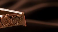 Rich milk chocolate bar with creamy texture and smooth surface broken to reveal airy interior structure for confectionery and dessert concepts.