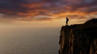 Silhouette of a person standing on a rocky cliff edge overlooking a vast ocean at sunset with dramatic golden and orange sky, conveying adventure and exploration themes.