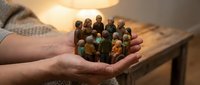 Group of diverse wooden figurines held in open palm, symbolizing community, teamwork, unity, and human connection for business and social concepts.