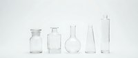 Empty glass laboratory equipment beakers flasks bottles arranged in row on white background for scientific research and chemical experiments.