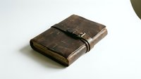 Vintage leather journal with worn brown distressed cover and metal buckle closure, isolated on white background for design and creative projects.