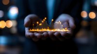 Hands cupping glowing miniature city with illuminated buildings and warm lights creating magical urban planning concept for business growth and development.