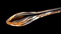 Golden honey dripping from wooden spoon against black background, natural sweetness flowing in smooth stream for culinary and food photography projects.