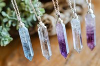 Collection of healing crystal pendant necklaces with amethyst and clear quartz stones in silver wire wrapping for spiritual jewelry and meditation.