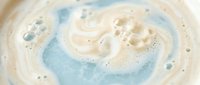 Creamy swirled foam texture with bubbles in soft blue and beige tones for spa wellness skincare cosmetic product backgrounds and natural organic beauty concepts.