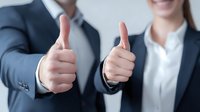 Business professionals showing thumbs up gesture, symbolizing approval, success, and positive feedback in corporate environment.