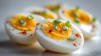 Gourmet deviled eggs with creamy orange yolk filling, garnished with fresh herbs and paprika spice. Elegant appetizer for parties and special occasions.