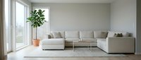 Modern living room with neutral beige sectional sofa, potted plant, and minimalist decor near bright windows for contemporary home interior design.