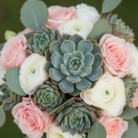 Elegant bridal bouquet with pink roses, white ranunculus and blue-green succulents for wedding ceremony and romantic celebrations.