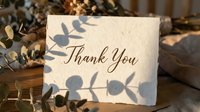 Handmade paper thank you card with elegant calligraphy, surrounded by dried flowers and eucalyptus leaves in warm natural light.