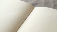 Open blank notebook with clean white pages spread wide showing textured paper surface ready for writing, journaling, sketching or creative projects.