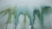 Abstract watercolor painting with green and teal paint drips flowing downward on white paper creating organic fluid patterns for artistic backgrounds.