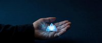 Close-up of hand holding glowing blue diamond crystal against dark background, representing wealth, luxury, investment, and precious gemstones for business concepts.