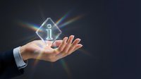 Male hand holding glowing information icon with light rays on dark background, representing digital support, customer service, help desk, and technology assistance solutions.