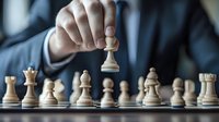 Professional in business suit making strategic move with white pawn on chess board during competitive game, demonstrating leadership and decision making in corporate setting.