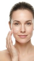 Young Caucasian woman applying white facial cream moisturizer on cheek with hand isolated on white background for skincare beauty routine and cosmetic products.