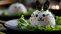 Cute bunny-shaped rice ball with nori ears and sesame seeds on fresh lettuce leaf, served on dark plate with soft bokeh background. Creative Asian cuisine styling.