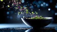 Fresh green herbs and leaves exploding from dark ceramic bowl against black background with water drops and blue bokeh lights, dramatic food photography.
