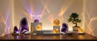 Zen meditation setup with amethyst crystals, salt lamps and bonsai tree creating warm ambient lighting for relaxation and spiritual wellness practices.