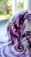 Purple and white swirled ice cream melting in bowl by sunny window, perfect for food photography, dessert advertising, and summer treat marketing campaigns.