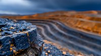 Dramatic close-up of layered rock formations with curved striations in contrasting blue and orange tones against stormy sky, showcasing geological patterns and textures.