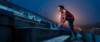 Young male athlete in sports attire performing parkour on urban concrete structure at dusk, demonstrating agility and strength for fitness, training, and action sports content.