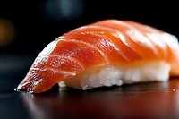 Fresh salmon nigiri sushi with glossy orange fish slice on seasoned rice, traditional Japanese cuisine for restaurant menus and culinary presentations.