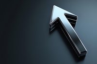 Metallic silver arrow pointing upward on dark background with dramatic lighting and reflective surface, symbolizing growth, success and forward movement.