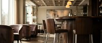 Upscale restaurant or hotel bar interior with dark wood furnishings, leather seating, and ambient lighting creating an elegant dining atmosphere for hospitality design projects.