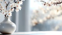 White ceramic vase with delicate cherry blossom branches creating peaceful spring ambiance against soft blurred background for home decor and wellness concepts.