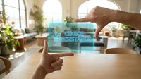 Hands holding transparent digital tablet displaying choice vs resistance concept in modern bright office with plants and natural lighting for business decisions.