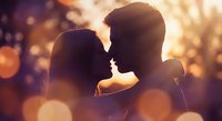 Romantic couple silhouettes touching foreheads in warm golden sunset light with dreamy bokeh background for love and relationship concepts.