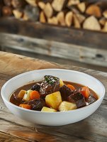 Hearty beef stew with tender meat chunks, carrots and potatoes in rich brown gravy, served in white bowl on rustic wooden table with natural lighting.