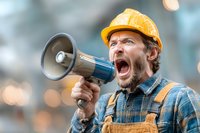 Angry construction worker shouting through megaphone at building site, expressing frustration during labor protest or safety announcement.