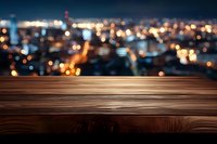 Empty wooden table surface against blurred city lights panorama at night, creating atmospheric background for product display or montage presentation.
