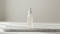 Clear liquid serum in white dropper bottle on marble surface for skincare, cosmetics, and beauty product design use.