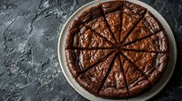 Freshly baked chocolate brownie cake cut into triangular slices on white plate against dark textured background, showcasing rich fudgy texture.