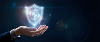 Businessperson holding glowing shield icon representing cybersecurity, data protection, and digital safety for enterprise security solutions.