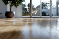 Polished hardwood flooring in modern minimalist room with large windows and decorative plant, low angle view showing natural wood grain texture and sunlight reflection.