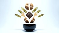 Assorted chocolate candies and confections floating above dark bowl on white background for culinary design projects and sweet treat concepts.