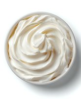 Creamy white cosmetic cream with swirled texture in glass jar isolated on white background for skincare and beauty product design applications.