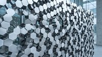 Geometric hexagonal wall installation with white and dark modules creating dimensional pattern against modern architecture backdrop.