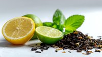 Fresh citrus fruits with lemon and lime halves alongside loose black tea leaves and mint leaves on white background for beverage preparation.