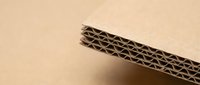 Corrugated cardboard edge showing internal fluted structure on neutral background for packaging and shipping industry applications.