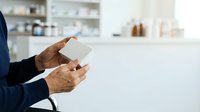 Senior man with dark skin tone holding blank white card in modern kitchen interior, suitable for business, healthcare, retail, and promotional campaigns.