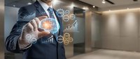 Businessman in dark suit and tie interacting with digital holographic interface displaying financial data, charts, and network icons in modern office environment for business technology concepts.