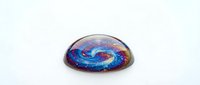 Cosmic galaxy spiral nebula encased in glass dome paperweight with vibrant blue purple colors isolated on white background for decorative home office use.